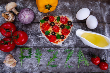 Heart shaped pizza ingredients. The name of the pizza is written in arugula.