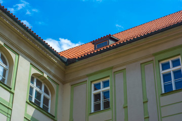 Fragment of the facade of a classic European building with white walls and light green trim against the sky. Summer.