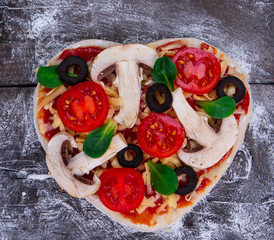 Cutting wooden board with traditional pizza ingridients on dark background, top view