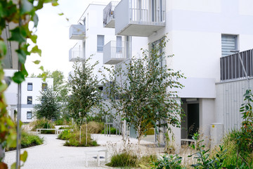 Sidewalk in a cozy courtyard of modern apartment buildings condo with white walls.