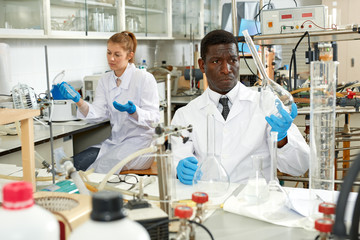 Male lab technicians with different glass tubes, girl on background