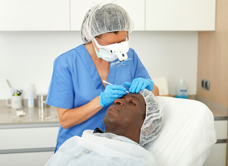 Cosmetician female in mask  is preparing client for mesotherapy