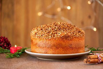 Almond cinnamon cake with christmas lights on wooden table. Close up  