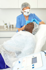 Dermatologist female preparing  man client before  aesthetic facial procedure