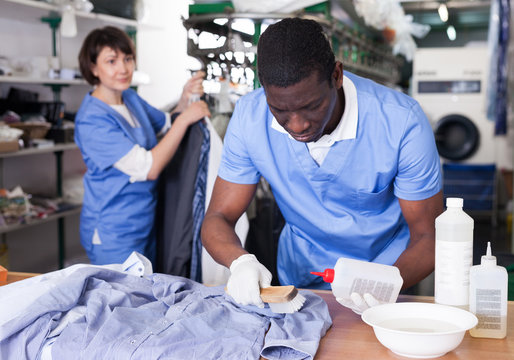 Man dry cleaning clothes in laundry