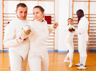 men and women fencers posing with foils  together