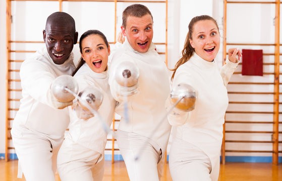 Smiling fencers posing with foils  together at fencing room - Powered by Adobe