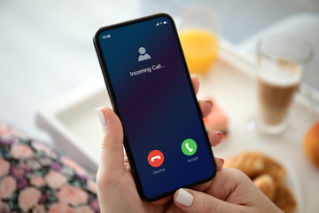 female hands holding phone with incoming call on the screen