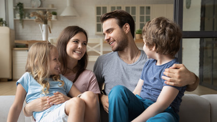 Smiling mother and father with kids sitting on couch