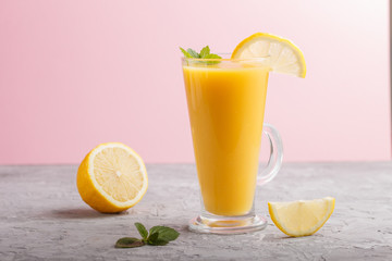 Glass of lemon drink on a gray and pink background. Side view