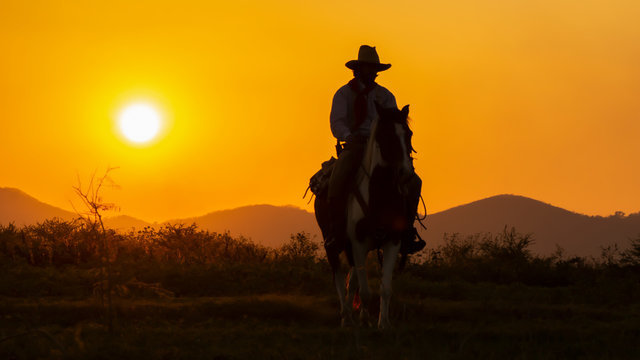 A lonely Cowboy riding horse  at sunset.