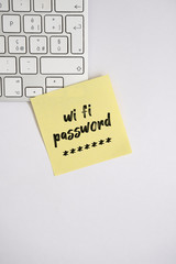 Yellow sticky note with text "Wi fi password " on the computer keyboard