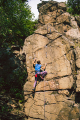 The girl climbs the granite rock.