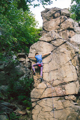 The girl climbs the granite rock.