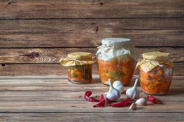 Various kimchi in glass jars on a brown wooden table.