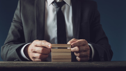 Businessman making a stack of wooden pegs