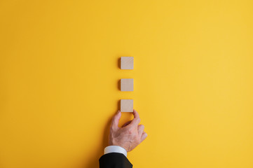 Placing three blank wooden blocks on yellow background