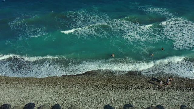 Tropical beach video loop showing seamless never ending footage with aerial bird eye view of green foaming ocean waves crushing against the coast line of Florida and overhead view of a seldom tourist
