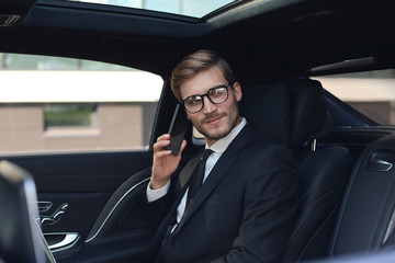 Thoughtful confident businessman talking on the phone while sitting in the car.