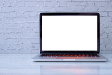 Blank screen on laptop, notebook on white brick wall texture background.