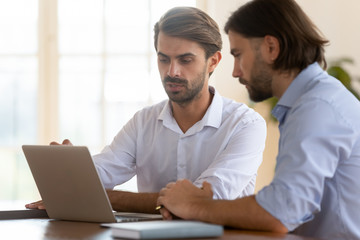 Obraz na płótnie Canvas Focused businessman salesman consult male client show presentation on laptop