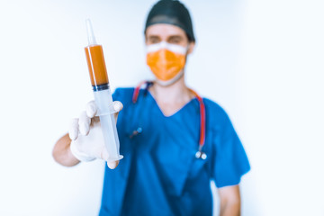 Medico chirurgo con camice blu e siringa con liquido arancione. Sfondo bianco.