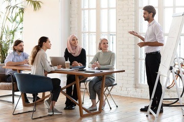 Confident businessman trainer give flip chart presentation at corporate training