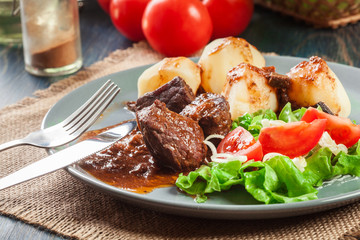 Pork meat stew served with potatoes and vegetable salad