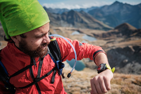 Young man looking at the gps track on his wearable, while hiking in the mountains in a clear autumn day