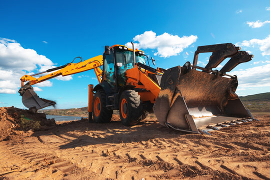 Wheel loader excavator with field background during earthmoving work, construction building