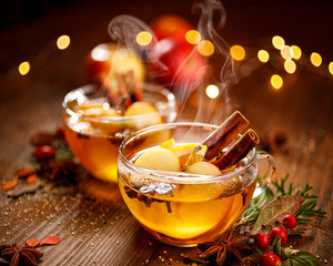 Mulled cider with apple slices, cinnamon, cloves, anise stars and citrus fruits in glass cups on a...