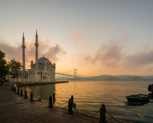 Obraz premium Ortakoy in the autumn. The Bosphorus at sunrise on a October morning. Ortakoy mosque and 15th of July martyrs bridge view. Istanbul city, Turkey country