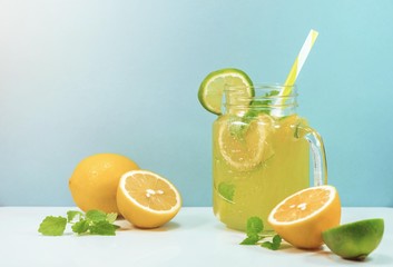 Lemonade drink of soda water, citrus and mint on the light blue background. Cocktail glass with...