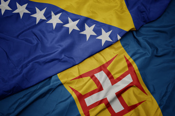 waving colorful flag of madeira and national flag of bosnia and herzegovina.