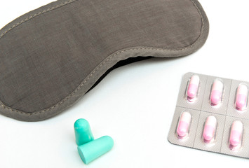 Eye shade, ear pugs and sleeping pills on the white background. The concept of general solution for sleep disorder, insomnia.