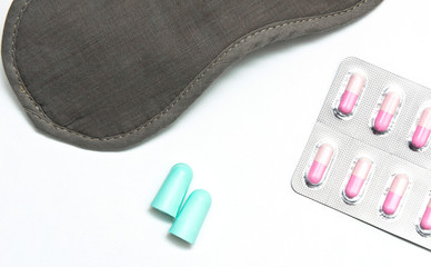 Eye shade, ear pugs and sleeping pills on the white background. The concept of general solution for sleep disorder, insomnia.