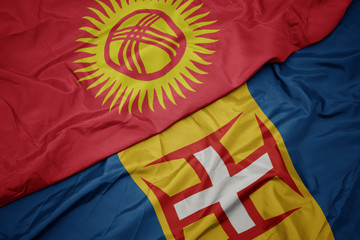 waving colorful flag of madeira and national flag of kyrgyzstan.