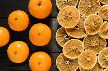 Whole oranges and dried slices isolated on black wooden table