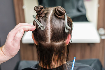 Hair stylist's hand divide women hair in sections with clips at hair salon. Hair extension in a professional beauty salon.