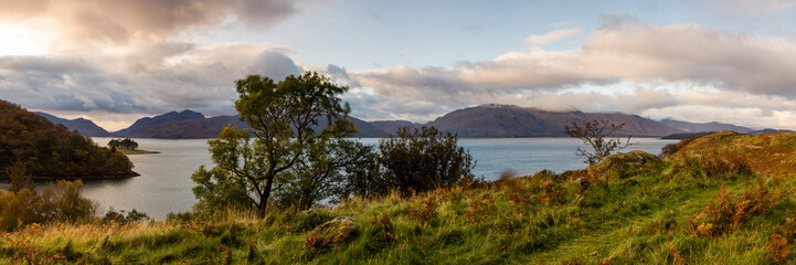 the beautiful kentallen bay in the argyll region of the highlands of scotland near glencoe and fort william in autumn during sunset showing golden trees and cloudy skies