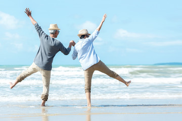 Fototapeta Asian Lifestyle senior couple jumping on the beach happy in love romantic and relax time.  Tourism elderly family travel leisure and activity after retirement in vacations and summer. obraz