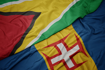 waving colorful flag of madeira and national flag of guyana.