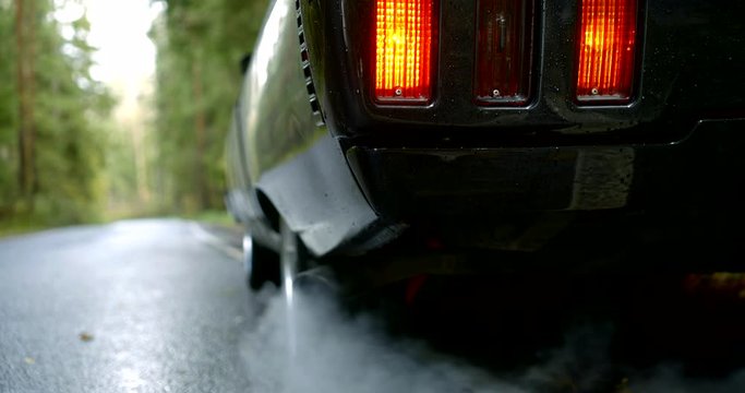 shiny car with lighted taillights emits smoke slow motion