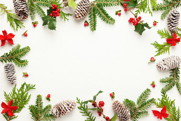 Fototapeta na wymiar Christmas background with pine cones, branches of holly with red berries and fir tree on white. Winter festive nature concept. Flat lay, copy space.