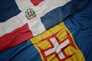 waving colorful flag of madeira and national flag of dominican republic.