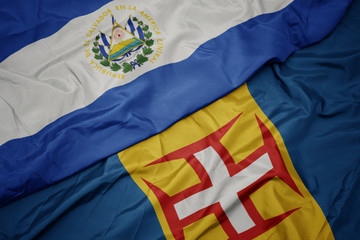 waving colorful flag of madeira and national flag of el salvador.