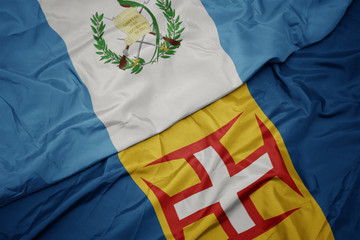 waving colorful flag of madeira and national flag of guatemala.