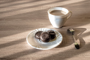 a cup of morning coffee latte with chocolate candies on a plate