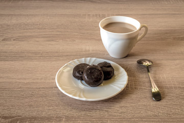 a cup of morning coffee latte with chocolate candies on a plate