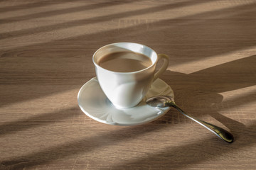 cup of morning latte coffee with saucer and spoon on the table